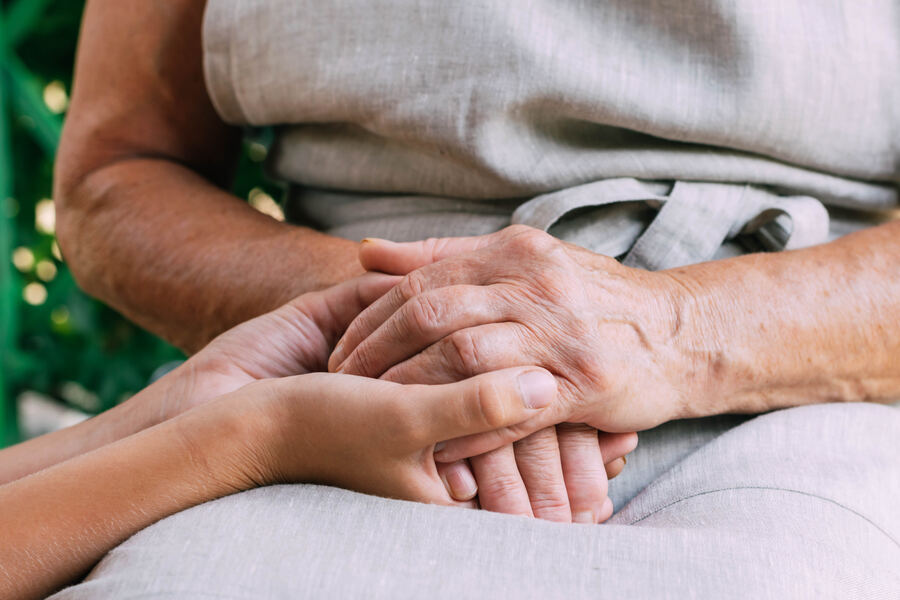 A daughter gently holding her elderly mother's hands